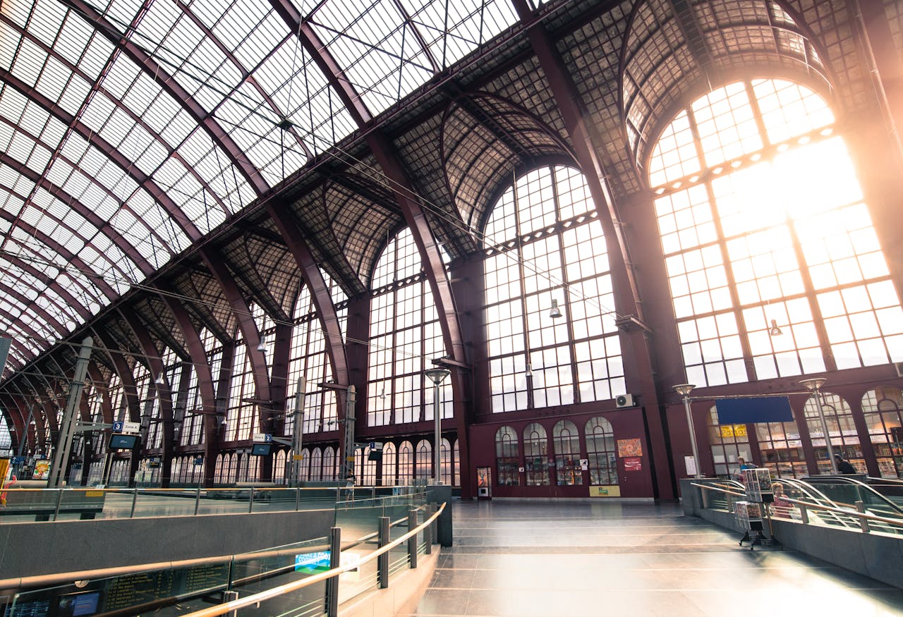 Interior of a bright, arched train station with sunlit windows in Europe.