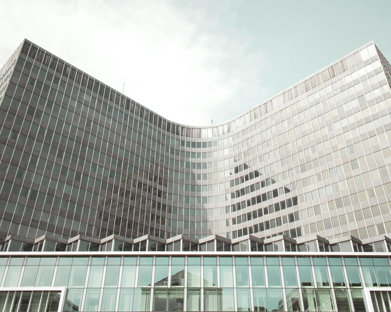 Sleek modern architecture with glass facade in Brussels, capturing urban reflections.