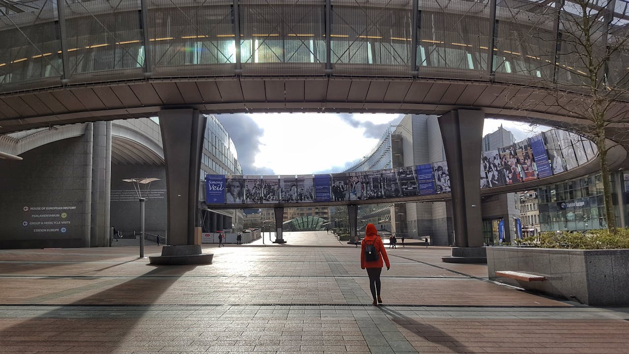A person in red walks through the European Parliament's modern architecture in Brussels.